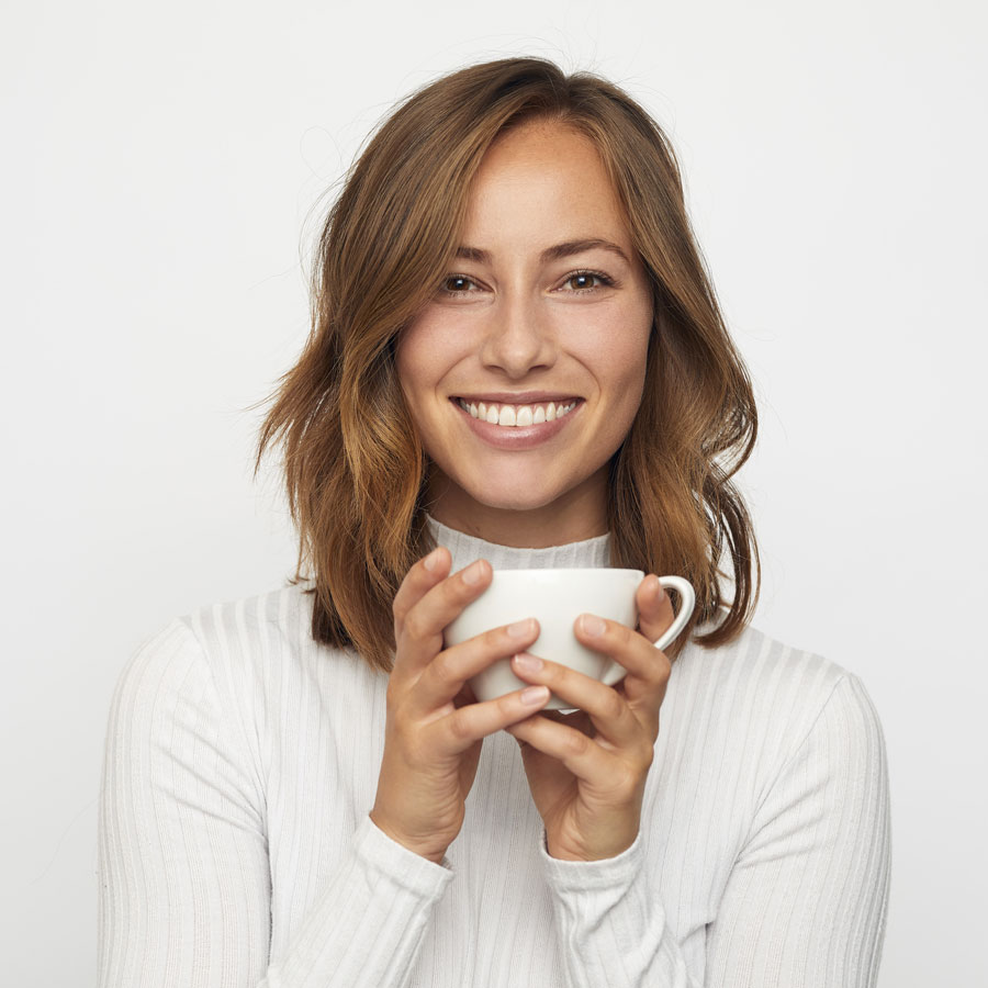 Frau mit Kaffee lächelt in die Kamera